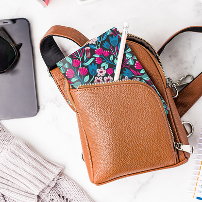A mockup of the Dark Floral mini notebook and a pencil in a purse.