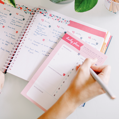 Person filling in their daily plan notepad