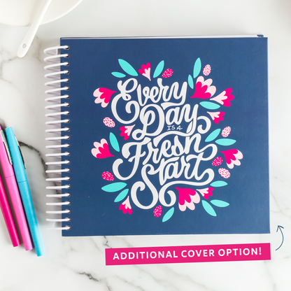 Additional cover option: Navy planner with 'Every Day is a Fresh Start' design on a marble surface with pens.