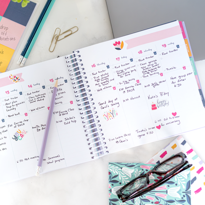 Open planner with colorful notes and a pencil on a white surface