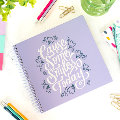 Purple planner with decorative text on a desk with stationery items