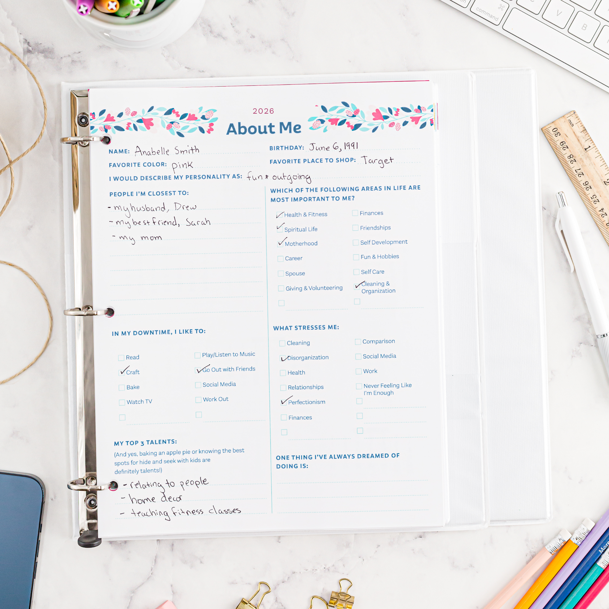 Personal information sheet titled 'About Me' in a binder on a desk with stationery items.