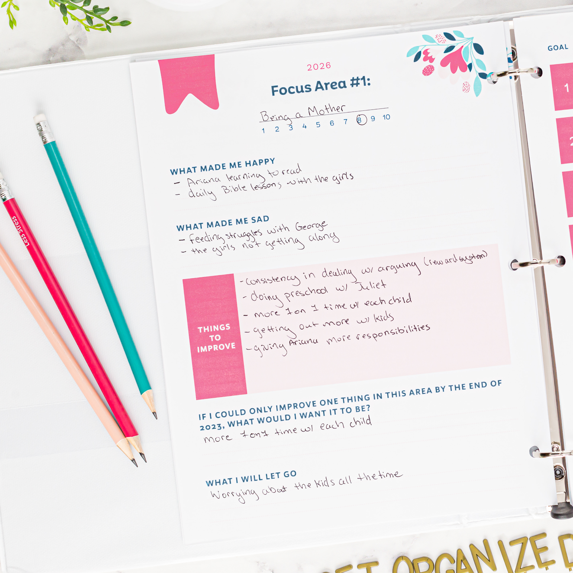 Focus areas planner page with reflective questions on a white surface with stationery items.